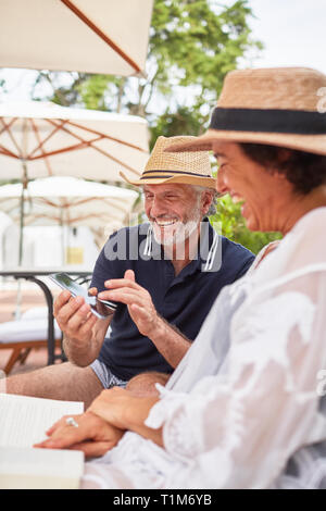 Happy mature couple using smart phone at resort poolside Stock Photo