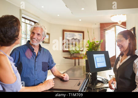 Mature couple checking in at hotel reception Stock Photo