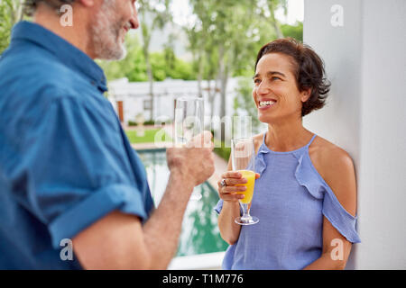 Happy mature couple drinking mimosas on hotel balcony Stock Photo
