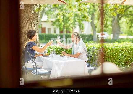 Mature couple toasting wine glasses at resort patio table Stock Photo