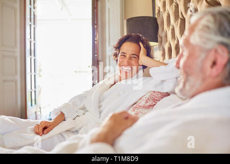 Happy, laughing mature couple relaxing on hotel bed Stock Photo