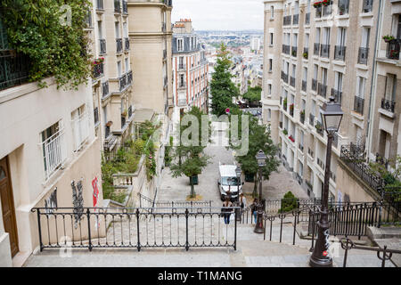 Paris, France - July 22, 2017:  Green streets of Paris in summer day. Cars on roads, people walking, beautiful architecture, cafe and shops. Stock Photo