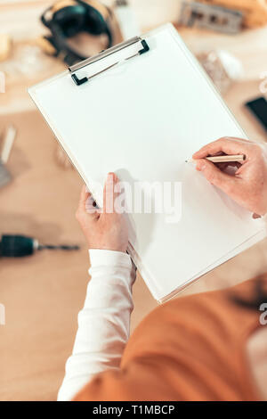 Female carpenter writing DIY project notes on clipboard note pad, mock up image Stock Photo