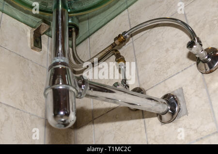 Pipe system under a glass sink in a bathroom Stock Photo