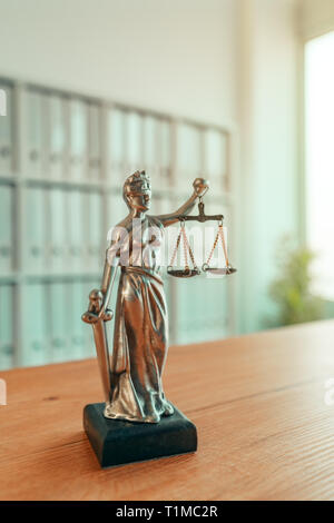 Lady Justice statue in law firm attorney office, blindfolded Justitia with balance scales and sword is personification of moral force in judicial syst Stock Photo