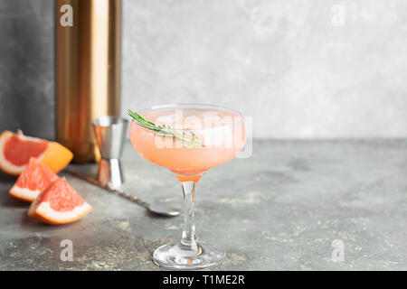 Refreshing summer cocktail grapefruit champagne rosemary juice in glass goblets on a light gray concrete background. Stock Photo