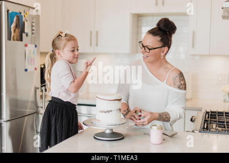 Mother and daughter decorating cake in kitchen Stock Photo
