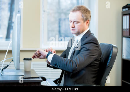 Adult man in suit looking at computer monitor during working day in office. Typing on the keyboard. Stock Photo