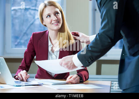 Business partners discussing documents and ideas at meeting. Man and woman in suits working with papers around table in the office. Workspace Stock Photo
