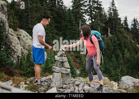 Couple hiking, stacking rocks Stock Photo