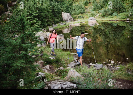 Couple hiking along lake in woods Stock Photo