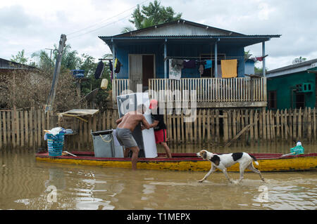 2015 flooding in Brazilian Amazon, family transports home appliances in small boat through flooded street at Taquari district, Rio Branco city, Acre State. Floods have been affecting thousands of people in the state of Acre, northern Brazil, since 23 February 2015, when some of the state’s rivers, in particular the Acre river, overflowed. Further heavy rainfall has forced river levels higher still, and on 03 March 2015 Brazil’s federal government declared a state of emergency in Acre State, where current flood situation has been described as the worst in 132 years. One of the worst affected ar Stock Photo