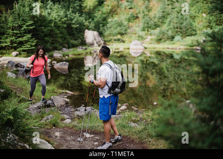 Couple hiking along lake in woods Stock Photo