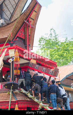 Local Torajan men carrying a coffin to a traditional long house at a funeral celebration in Indonesia Stock Photo