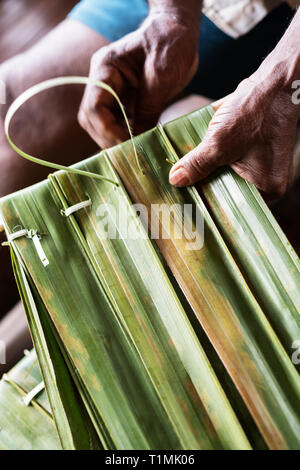 Indigenous Alfur people of the Nuaulu group stitching palm leaves, Seram island, Maluku, Indonesia Stock Photo