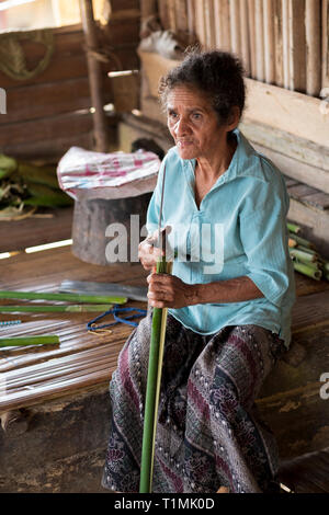 Indigenous Alfur people of the Nuaulu group stitching palm leaves, Seram island, Maluku, Indonesia Stock Photo