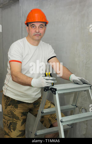 Elderly electrician with a tool and stepladder Stock Photo