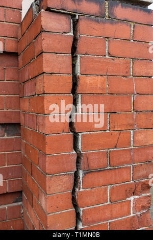 Really big 12.7mm or 1/2 inch crack going vertically down splitting a red brick wall into two Stock Photo