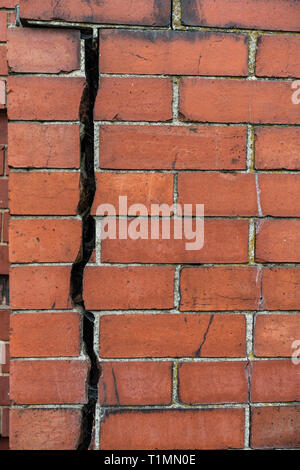 Really big 12.7mm or 1/2 inch crack going vertically down splitting a red brick wall into two Stock Photo