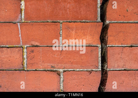 Really big 12.7mm or 1/2 inch crack going vertically down splitting a red brick wall into two Stock Photo