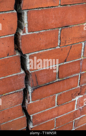 Really big 12.7mm or 1/2 inch crack going vertically down splitting a red brick wall into two Stock Photo