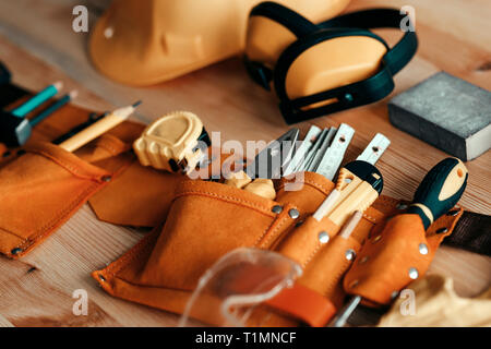 Carpentry tools and protective equipment on the desk in woodwork workshop, selective focus Stock Photo