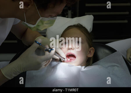 Little girl at dentist office, getting local anesthesia injection into gums, dentist numbing gums for dental work. Pediatric dental care concept. Stock Photo