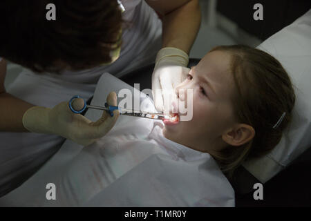 Little girl at dentist office, getting local anesthesia injection into gums, dentist numbing gums for dental work. Pediatric dental care concept. Stock Photo