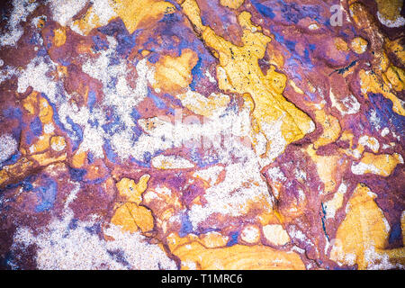 Purple, yellow, orange, white sedimentary rocks - colourful rock layers formed through cementation and deposition - abstract graphic design background Stock Photo