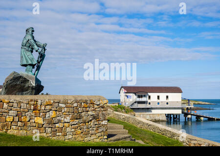 Statue of Coxswain Richard (Dic) Evans with new Moelfre RNLI Lifeboat Station beyond. Moelfre Isle of Anglesey Wales UK Stock Photo