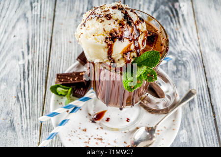 Iced chocolate cocktail. Cold summer sweet drink with cocoa, vanilla ice cream ball and mint leaves. wooden background copy space Stock Photo
