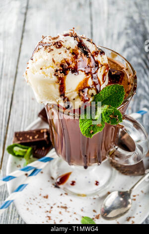 Iced chocolate cocktail. Cold summer sweet drink with cocoa, vanilla ice cream ball and mint leaves. wooden background copy space Stock Photo