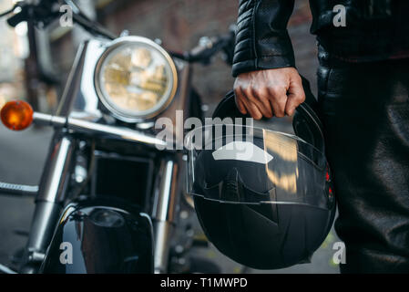 Biker in leather jacket with helmet in hand Stock Photo