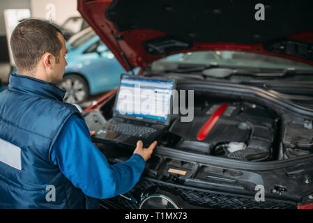 Engineer makes computer diagnostics of car engine Stock Photo