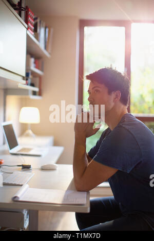 Thoughtful man working at desk in home office Stock Photo