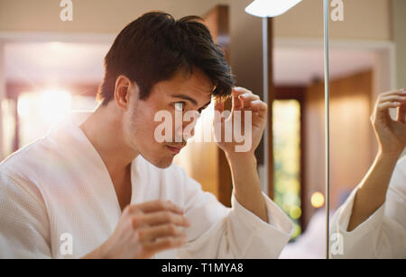 Man checking hair in bathroom mirror Stock Photo
