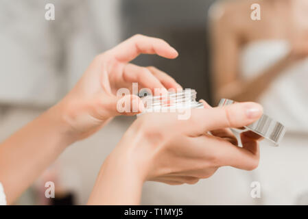 Close up of hands using hand cream. woman wrapped in towels in the bathroom.  beauty makeup and skincare concept Stock Photo