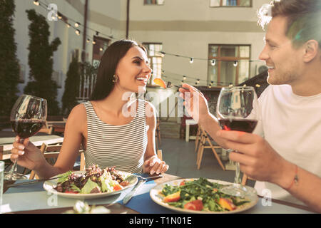 Smiling short-haired man with glass of red wine in one hand Stock Photo