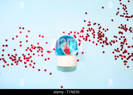 Beautiful snow ball with watermelon and glitter inside on pastel blue background Stock Photo