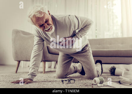 Aged sick white-haired seventy-year mister suffering from severe heartache Stock Photo