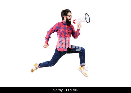 full length studio portrait of bearded hipster man in glasses, jumping and shouting in megaphone, isolated on white background Stock Photo