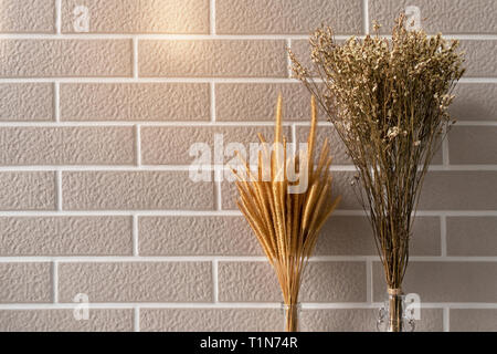brown dry grass and small flower with soft light brick wall interior background Stock Photo