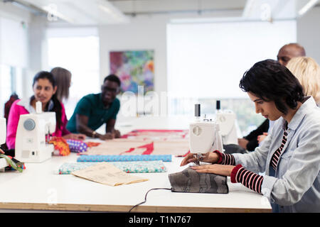 Fashion design students working at sewing machines in studio Stock Photo