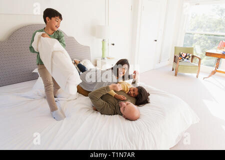 Happy family pillow fighting on bed Stock Photo