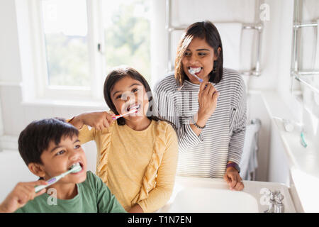 Portrait happy family brushing teeth in bathroom Stock Photo
