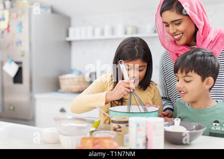 Mother in hijab baking with children in kitchen Stock Photo