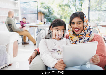 Happy mother in hijab and daughter using digital tablet Stock Photo