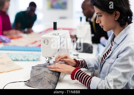 Focused female fashion designer using sewing machine Stock Photo