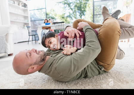 Playful father and son hugging on floor Stock Photo