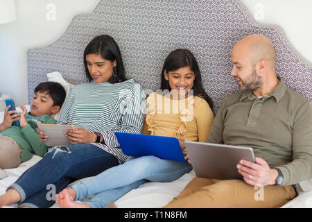 Family using technology on bed Stock Photo